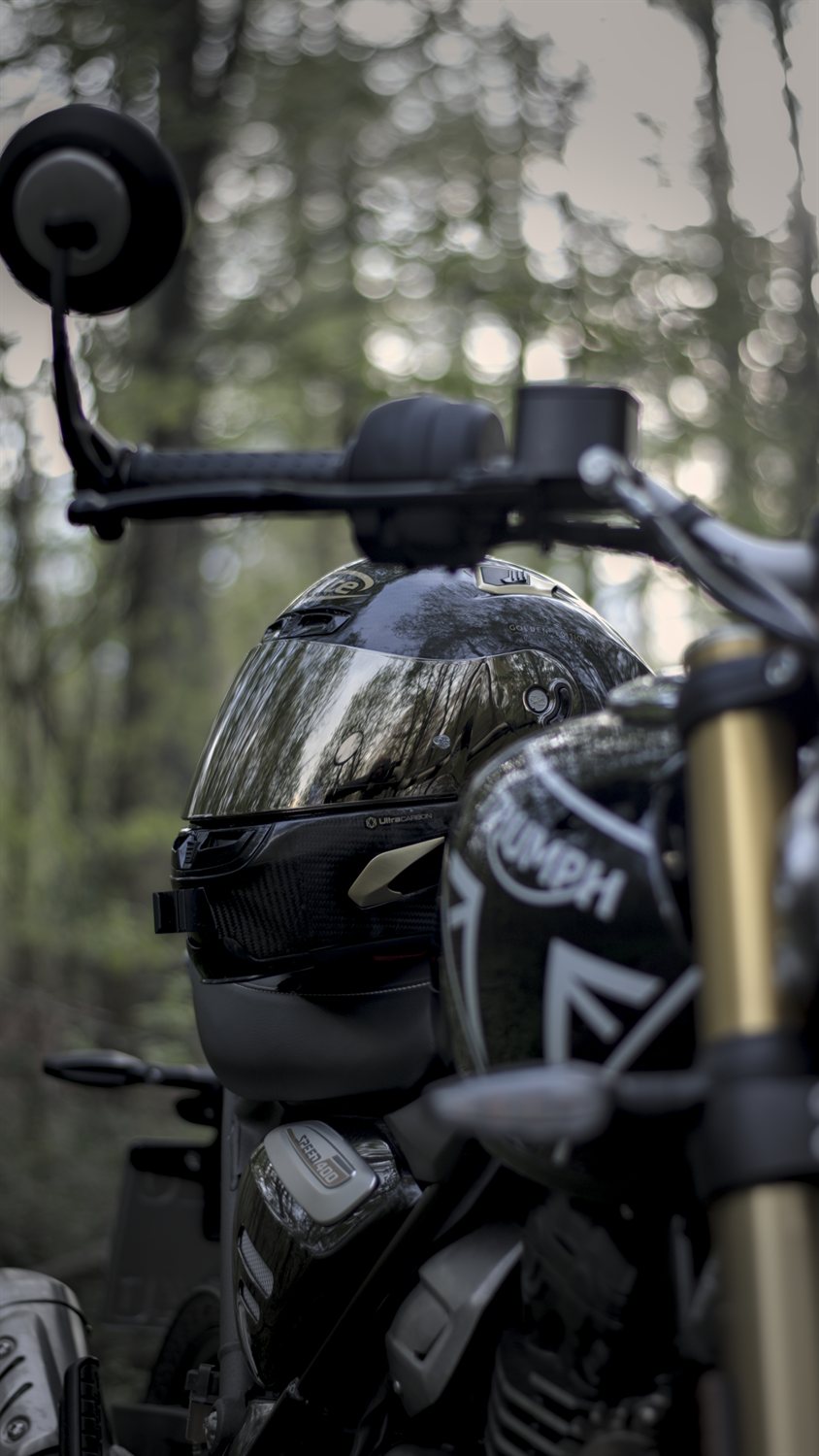 Triumph Speed 400 motorcycle with a helmet resting on it in a forest