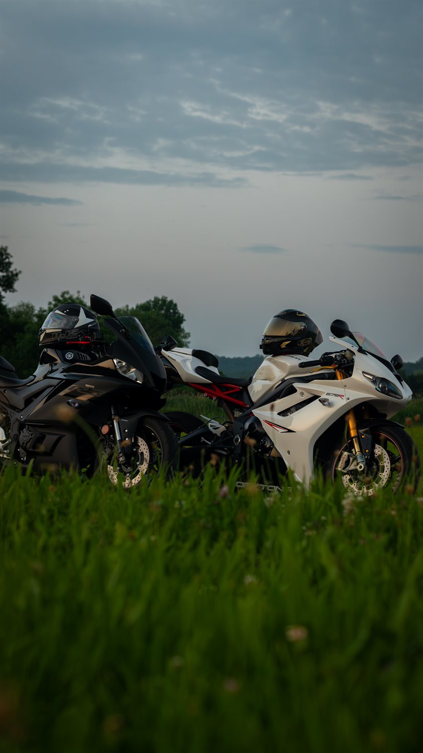 A black and a white sportbike in a field at dusk