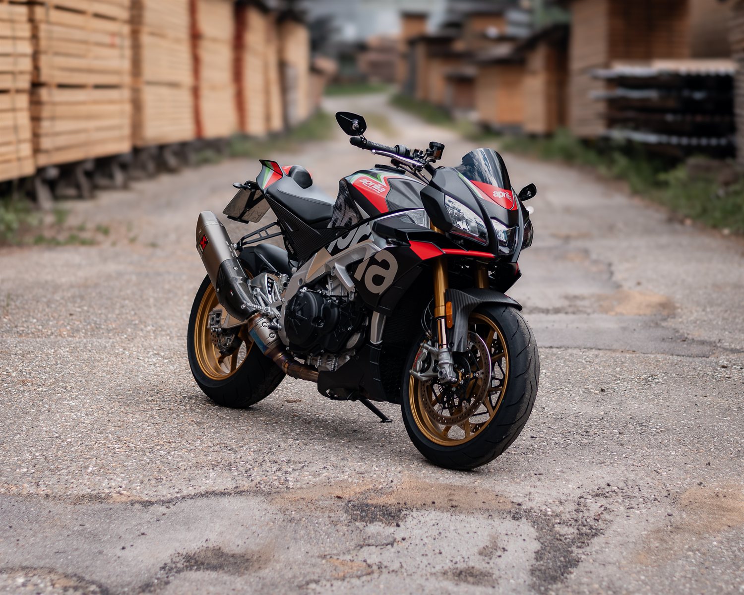 Aprilia Tuono naked motorcycle parked between stacks of timber