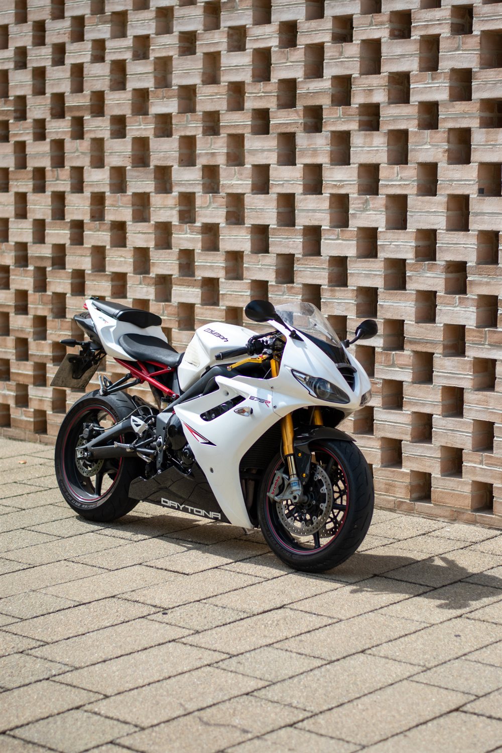 White Triumph Daytona 675R against a patterned brick wall